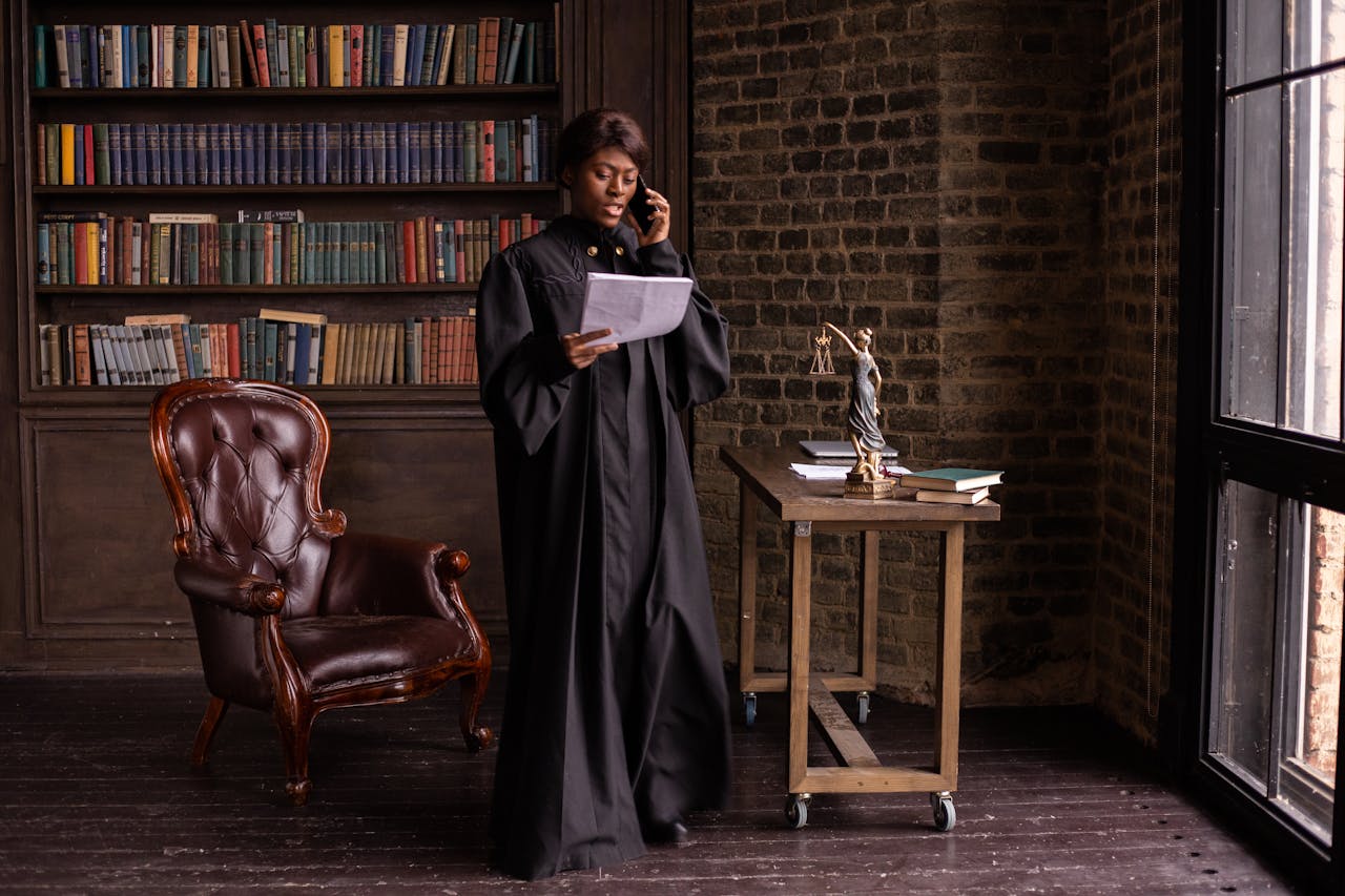 African American female judge talking on phone in a library, reviewing legal documents.