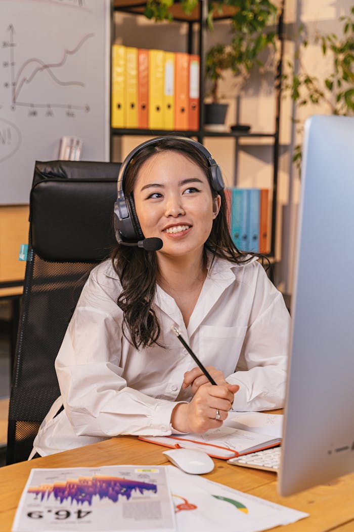 Professional woman with headset working at desk, engaged in a virtual meeting.