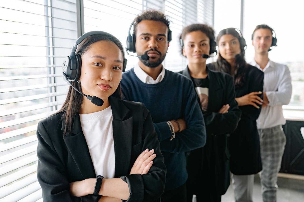 A diverse group of call center employees wearing headsets in a modern office setting.